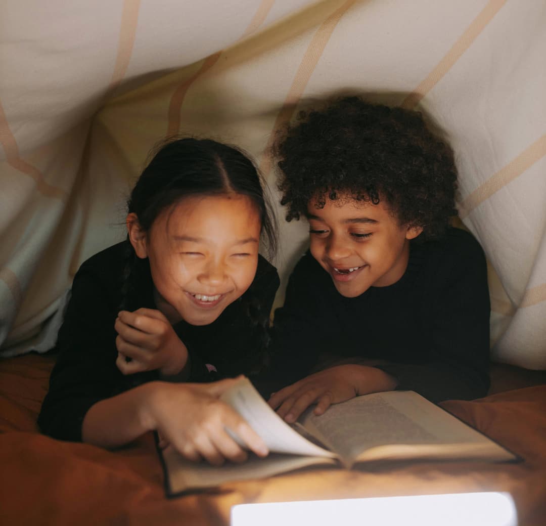 children reading under a blanket